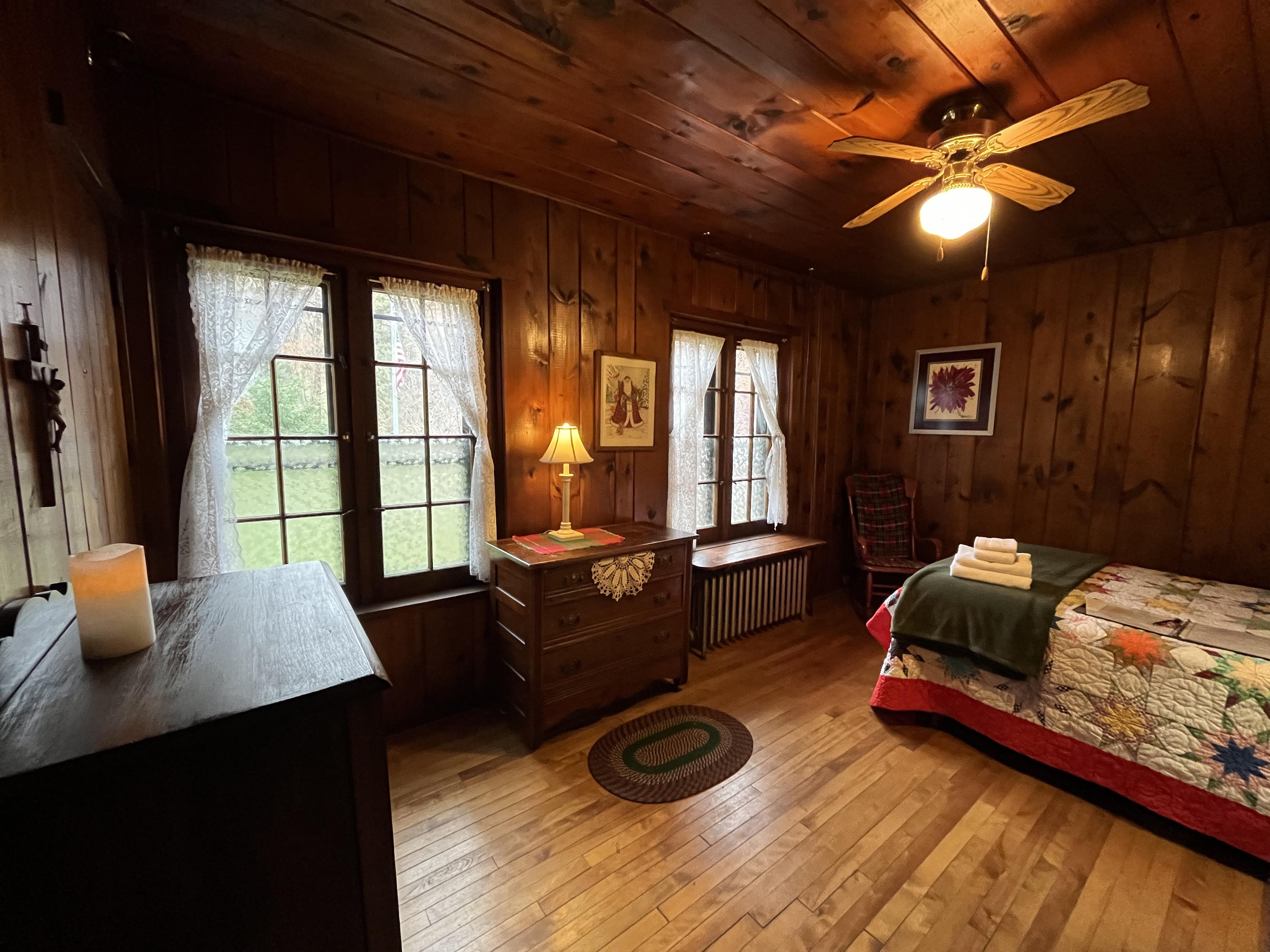 Log Lodge bedroom with knotty pine walls, quilt bedding, and french doors